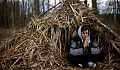 young man meditating in front of a straw shelter